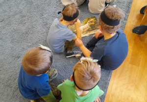Chłopcy oglądają trójwymiarowe plansze z dinozaurami.